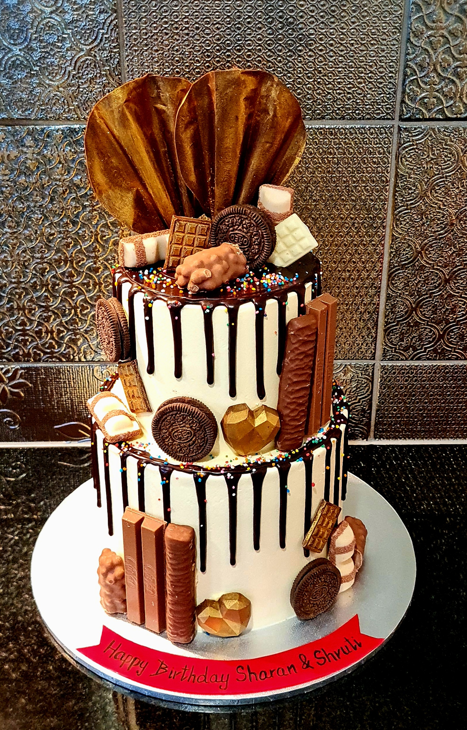 Chocolate Overloaded Two-Tier Drip Cake with Oreos, Kit-Kat, wafers, chocolate hearts and fan decoration for Sharan & Shruti's birthday celebration