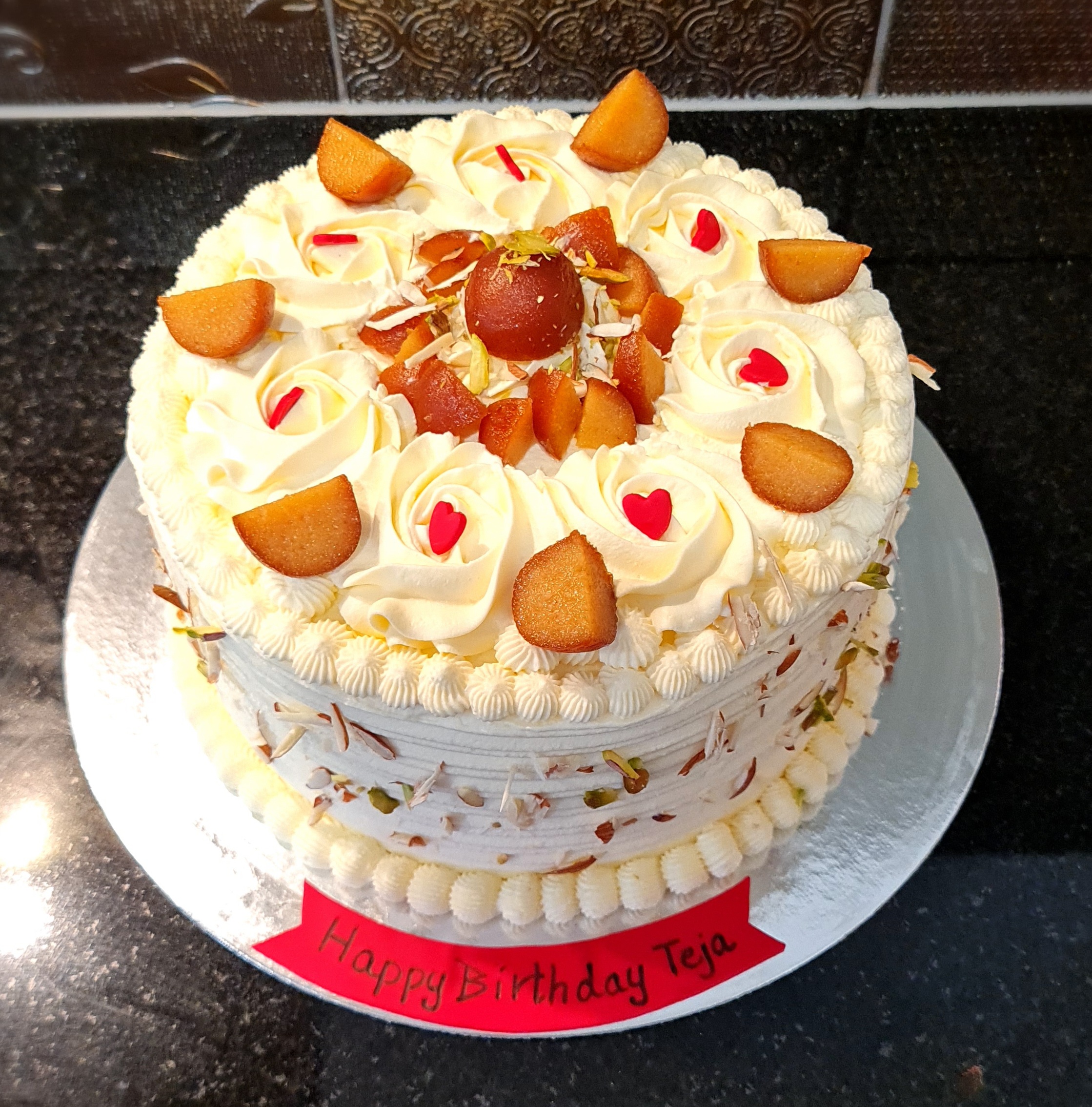 Gulab Jamun Fusion Cake with traditional Indian sweets, cream rosettes and nuts for Teja's birthday celebration
