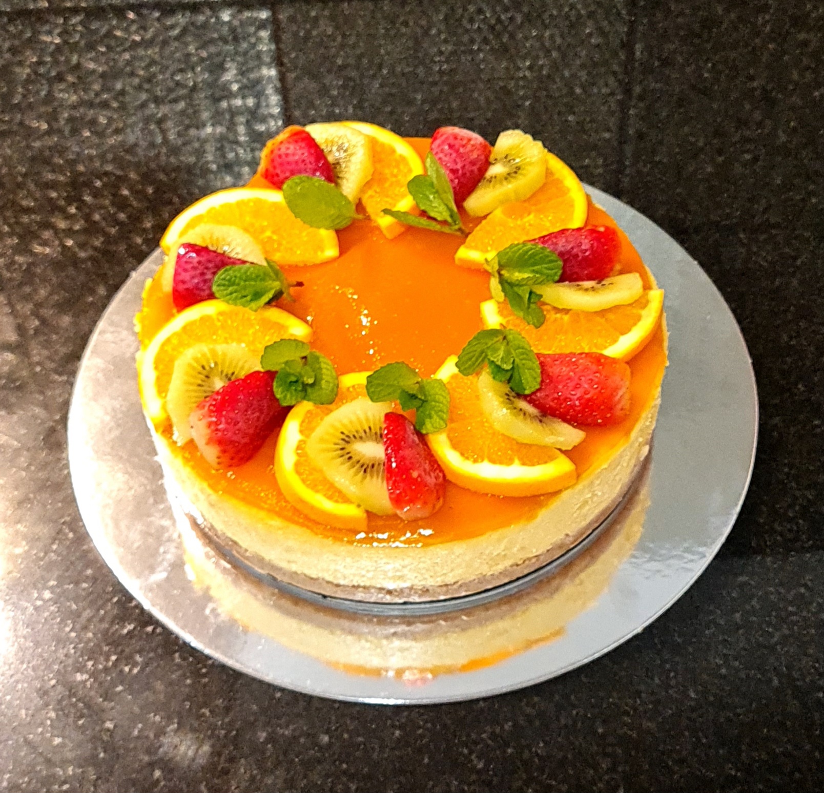 Mixed Fruit Fresh Cream Cake with orange glaze, kiwi, strawberries, oranges and mint leaves