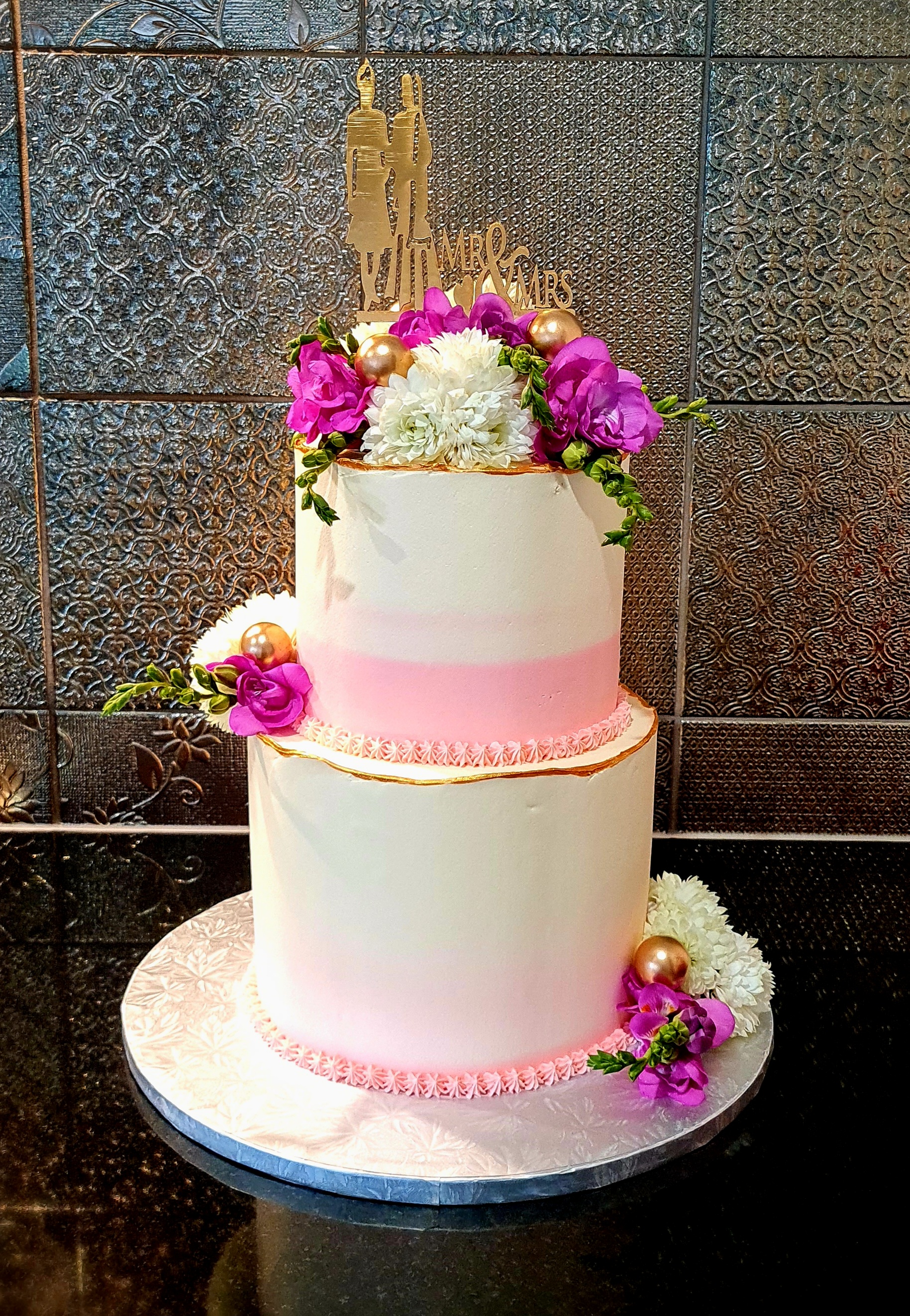 Two-tier white and pink ombre cake with fresh flowers and 'Mr & Mrs' topper for engagement/wedding