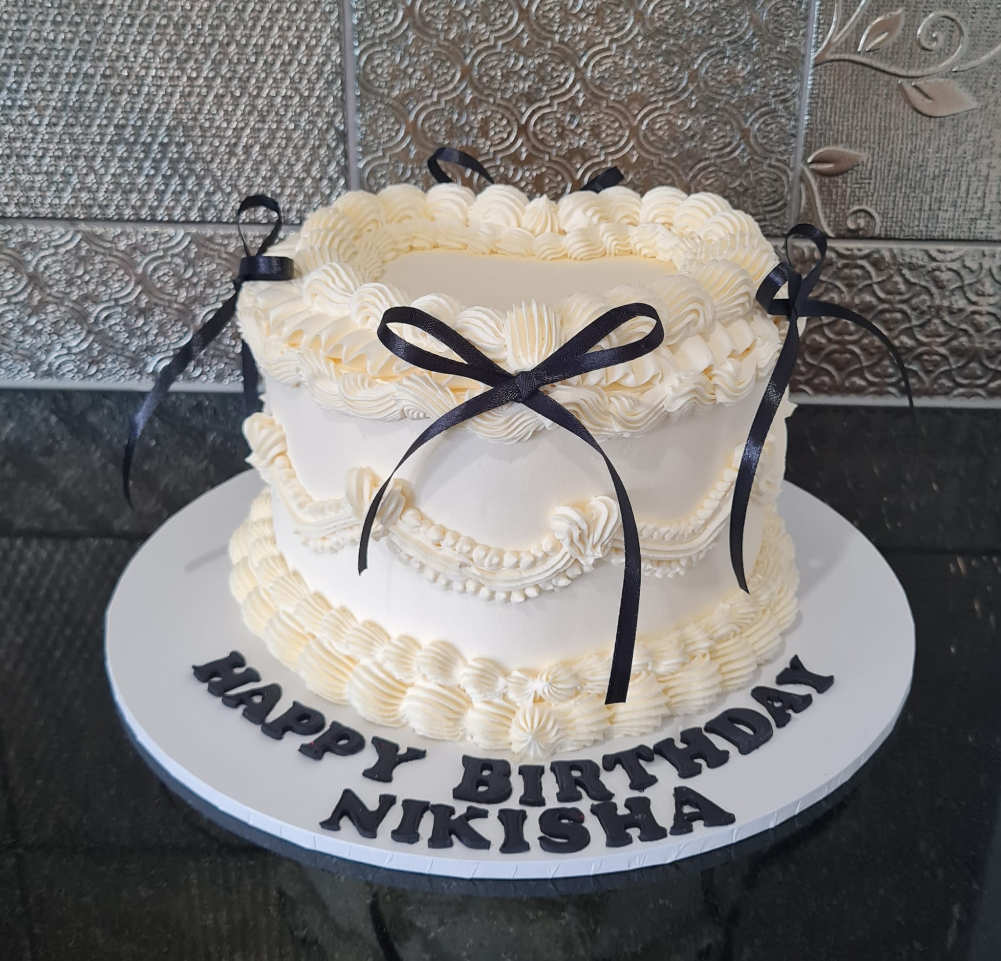 Vintage style white birthday cake with black ribbons for Nikisha's elegant celebration